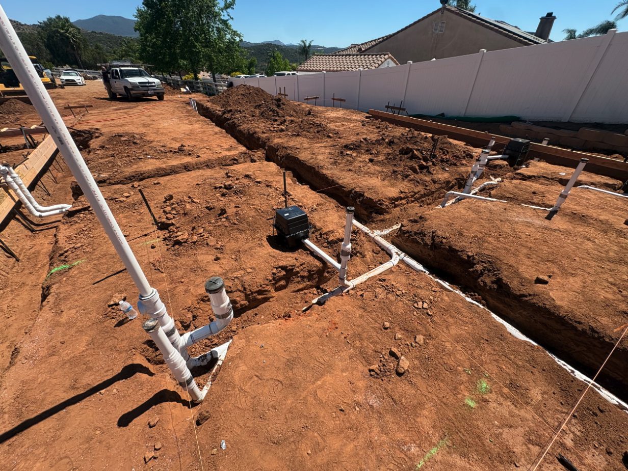 Ground-up site with PVC sewer and waste lines, cleanouts, and vent stubs in open trenches